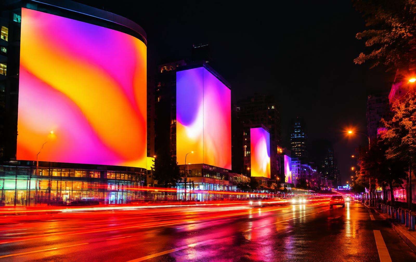 Large illuminated digital billboards along a city street at night